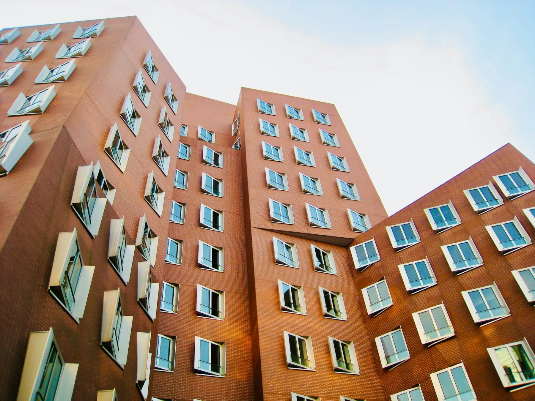 Torres residenciais de tijolo com janelas e sacadas, vistas de baixo contra o céu claro